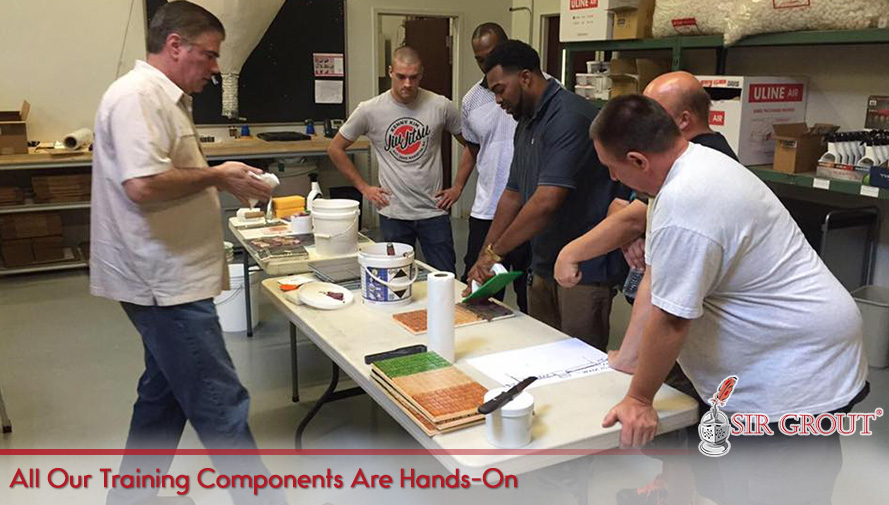 Franchisees Attending Hands-On Surface Restoration Training Workshop Gathered Around Instructor's Table With Different Products and Materials